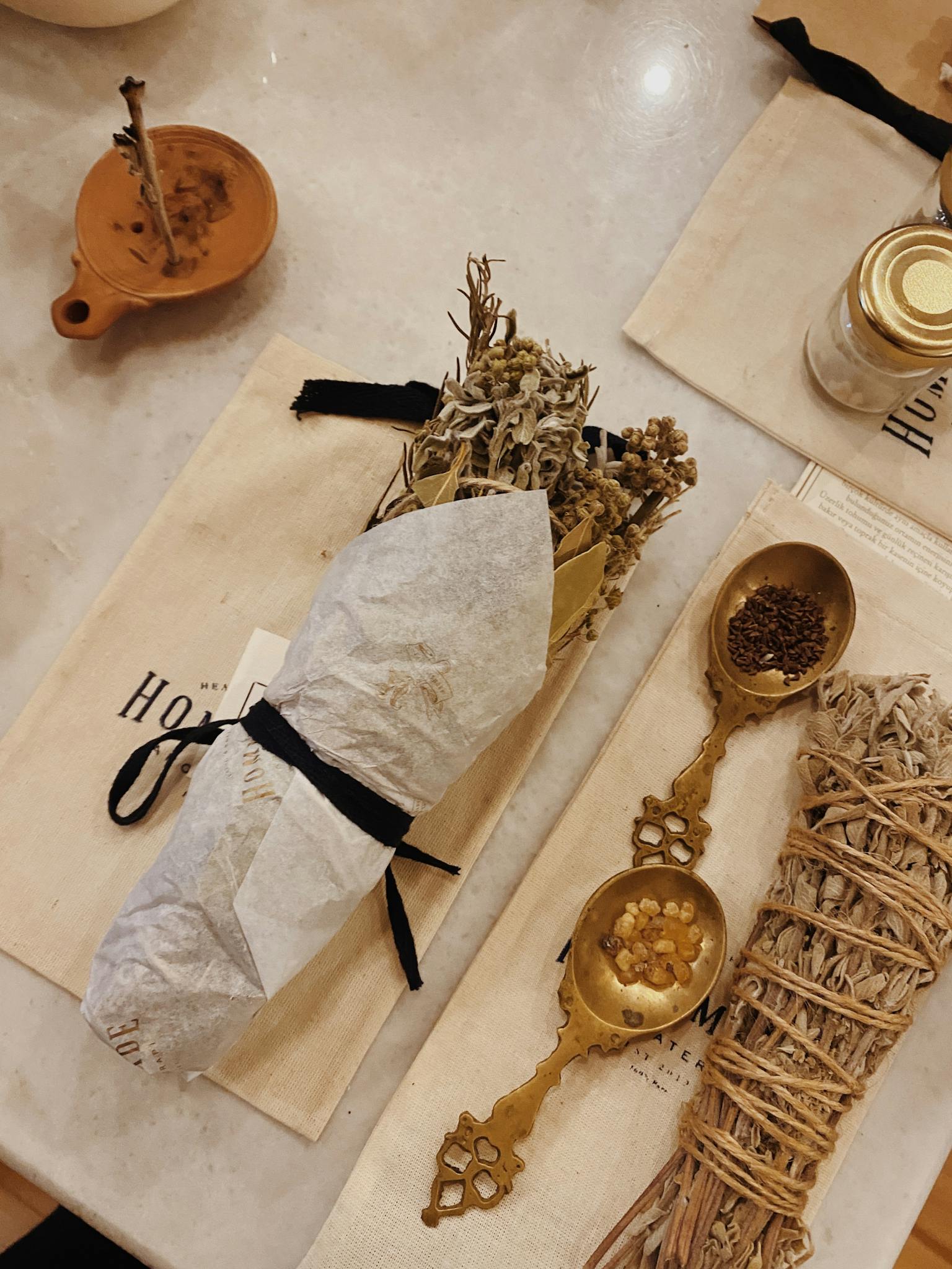 Close-up of a rustic herbal arrangement with dried flowers and ornate spoons on a table.