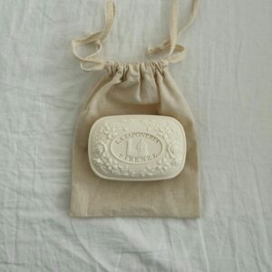 White artisanal soap displayed on a natural fabric linen bag.